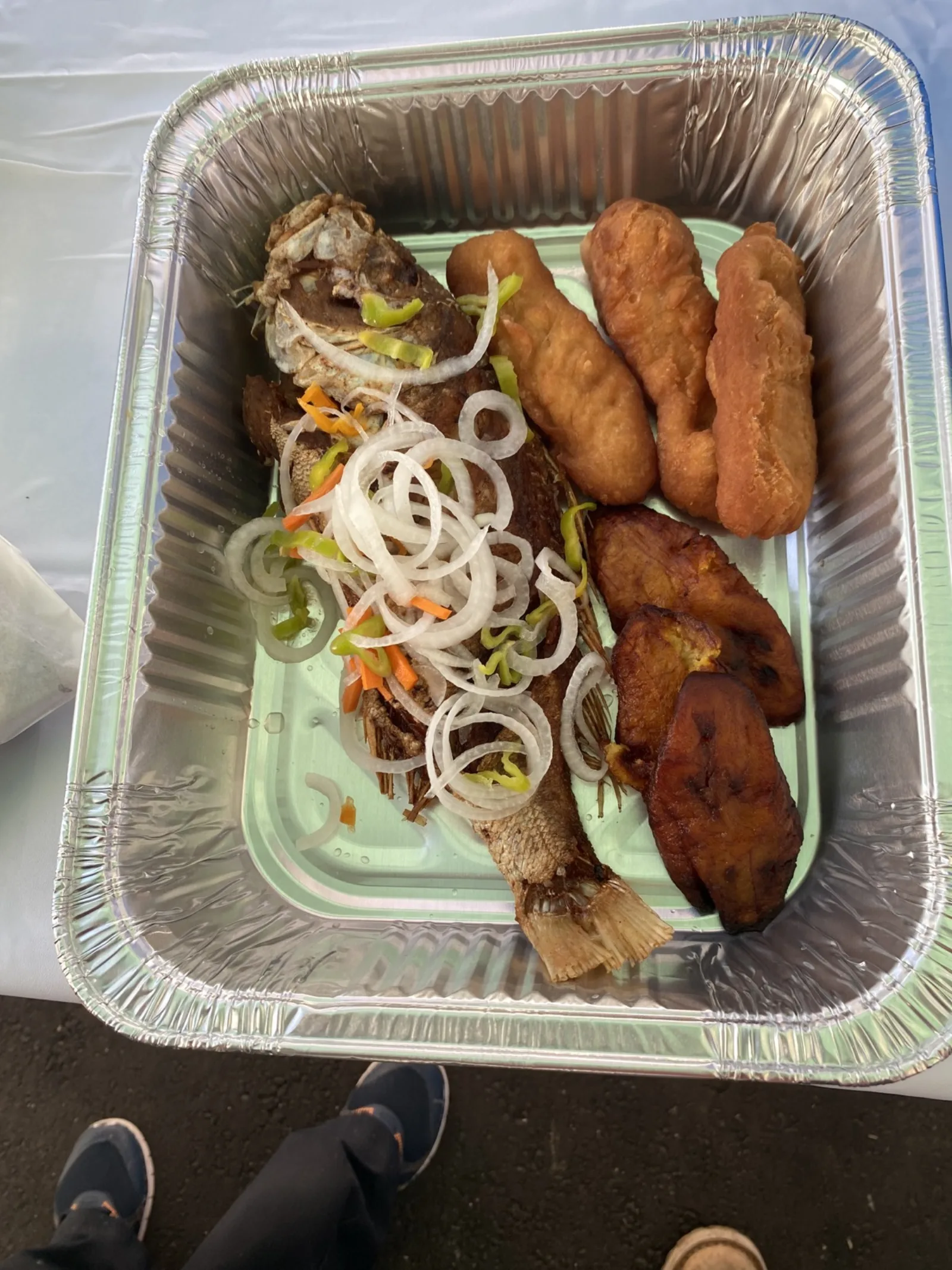 A freshly packed Lunch Box meal with fish, fried dumplings and plantain